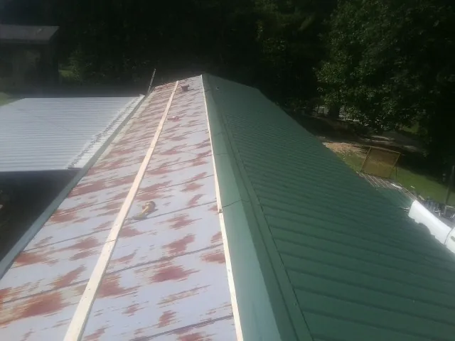 Old rusted panels beside newly installed green metal roofing — Wind Damage Roof Repair by Roofing Brothers in Colleyville