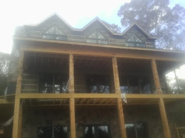 Dormers and porch framing on a large log home under construction — Roof Coating work by our crew in Colleyville