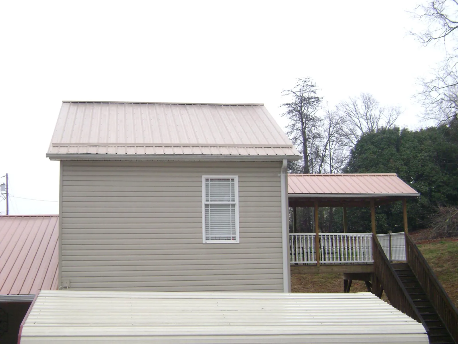 Tan metal roofs on a two story addition and attached porch, from a Roof Replacement job in Colleyville