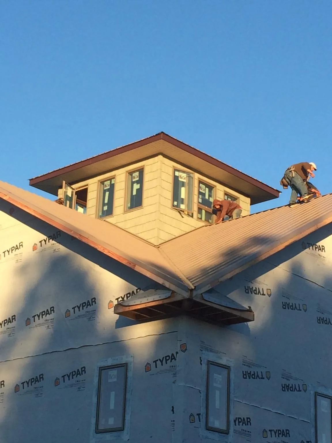 Roofers working around a rooftop cupola on a new metal roof at sunset — Roof Waterproofing in Colleyville by Roofing Brothers